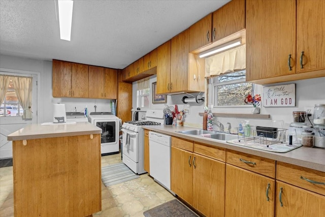 kitchen with white appliances, a textured ceiling, washer / dryer, a kitchen island, and sink