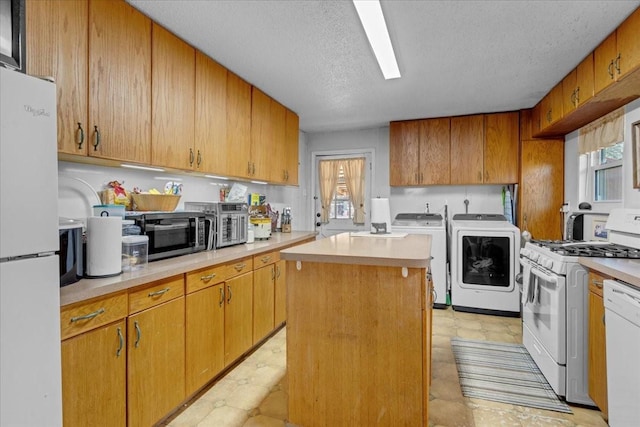 kitchen featuring a kitchen island, white appliances, a textured ceiling, and independent washer and dryer