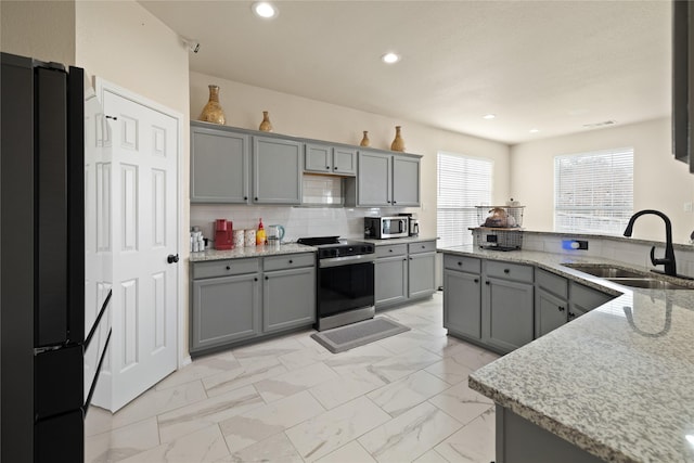 kitchen with sink, gray cabinetry, black fridge, and range with electric cooktop