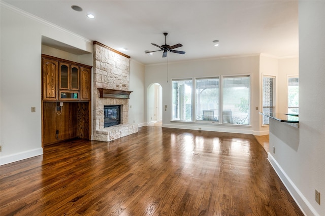 unfurnished living room featuring crown molding, dark hardwood / wood-style floors, a fireplace, and ceiling fan