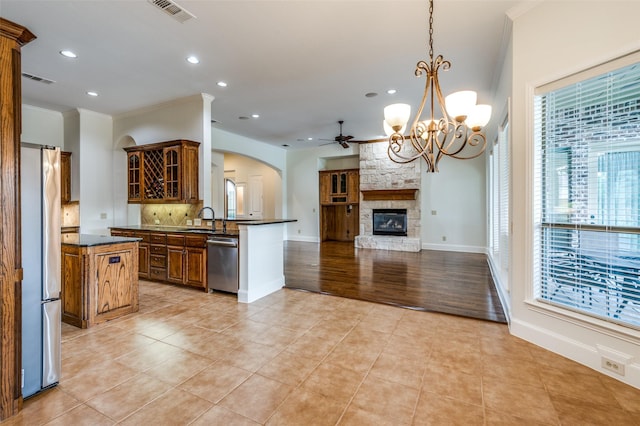 kitchen with stainless steel appliances, decorative backsplash, hanging light fixtures, kitchen peninsula, and crown molding