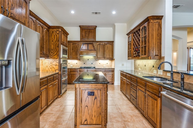 kitchen featuring appliances with stainless steel finishes, sink, dark stone counters, a center island, and decorative backsplash