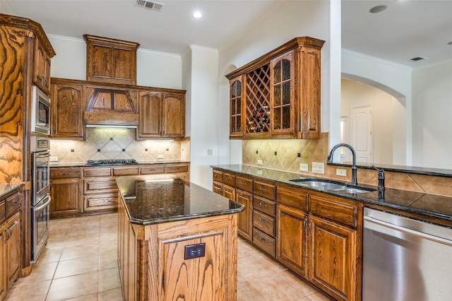 kitchen with appliances with stainless steel finishes, a kitchen island, dark stone countertops, sink, and backsplash