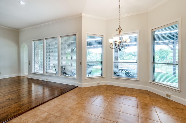 empty room with light tile patterned floors, a wealth of natural light, and ornamental molding