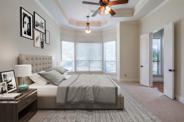 bedroom featuring light carpet, ceiling fan, a tray ceiling, and crown molding