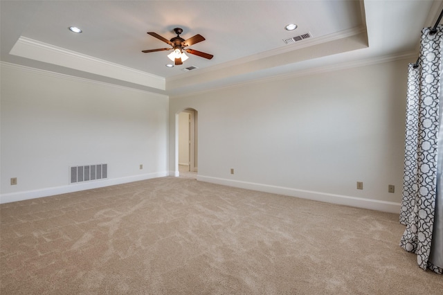 carpeted spare room with ceiling fan, ornamental molding, and a raised ceiling