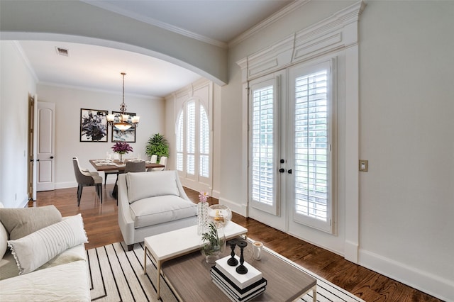 living room with wood-type flooring, crown molding, and a chandelier