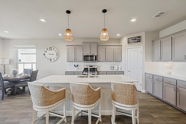 kitchen with visible vents, gray cabinets, dark wood-style floors, appliances with stainless steel finishes, and light countertops