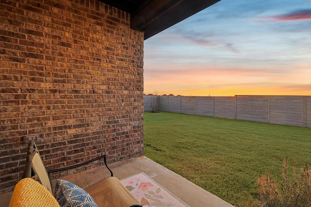 yard at dusk featuring a fenced backyard