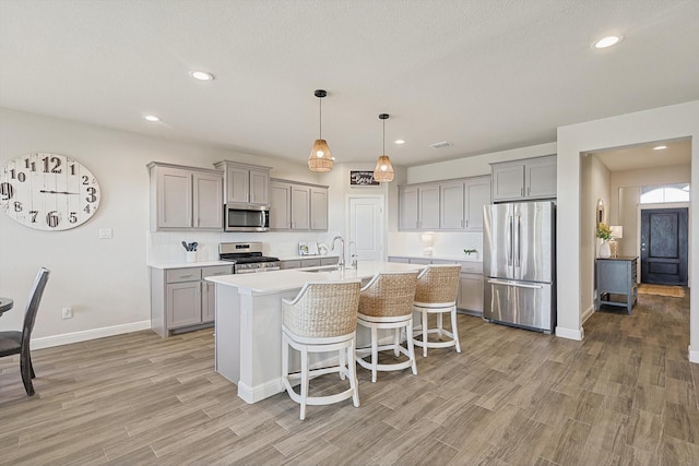 kitchen featuring a sink, gray cabinetry, light wood finished floors, and stainless steel appliances