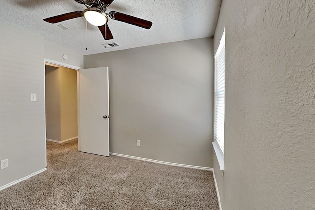 unfurnished room with ceiling fan, a textured ceiling, and carpet