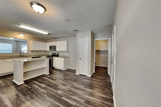 kitchen featuring appliances with stainless steel finishes, white cabinets, sink, dark hardwood / wood-style flooring, and light stone counters