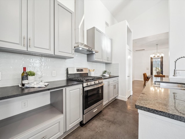 kitchen featuring decorative light fixtures, wall chimney range hood, an inviting chandelier, stainless steel gas stove, and sink