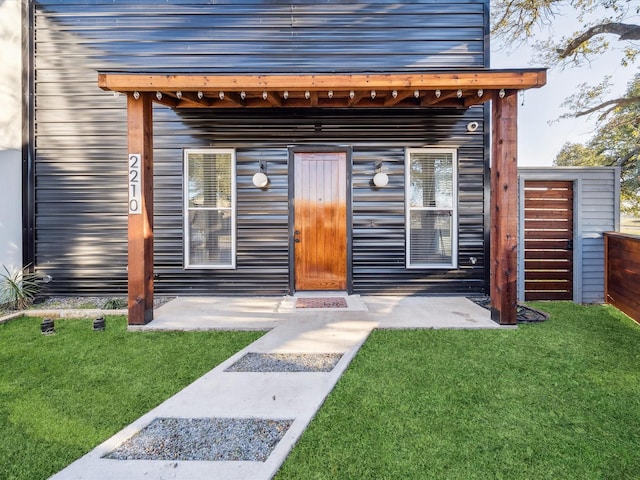 view of exterior entry with a patio and a yard