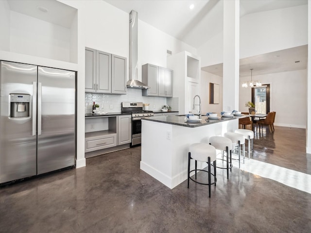 kitchen featuring a kitchen bar, a kitchen island with sink, appliances with stainless steel finishes, and gray cabinets