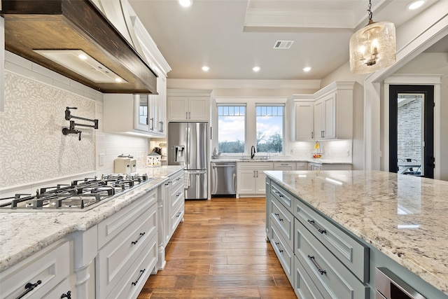 kitchen with sink, hanging light fixtures, stainless steel appliances, white cabinets, and decorative backsplash