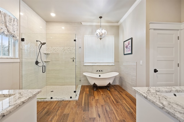 bathroom featuring shower with separate bathtub, hardwood / wood-style floors, vanity, ornamental molding, and a notable chandelier