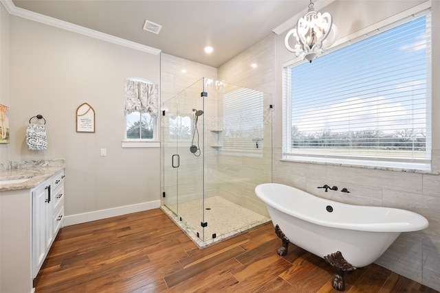 bathroom featuring hardwood / wood-style floors, vanity, a notable chandelier, ornamental molding, and plus walk in shower