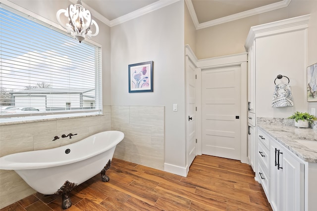 bathroom with ornamental molding, a bath, vanity, and an inviting chandelier