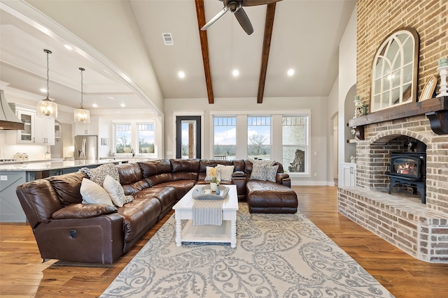 living room featuring hardwood / wood-style flooring, ceiling fan, beam ceiling, and a towering ceiling