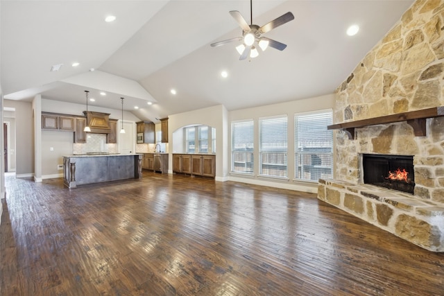 unfurnished living room featuring dark wood-style flooring, a fireplace, baseboards, and ceiling fan