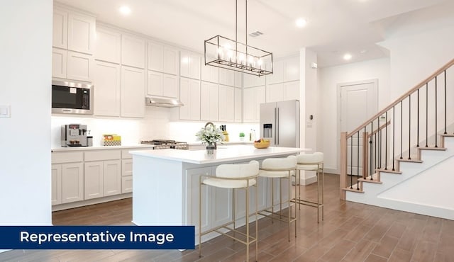 1804 Wittington Pl, Farmers Branch, TX 75234 - kitchen with appliances with stainless steel finishes, under cabinet range hood, dark wood finished floors, white cabinets, and recessed lighting