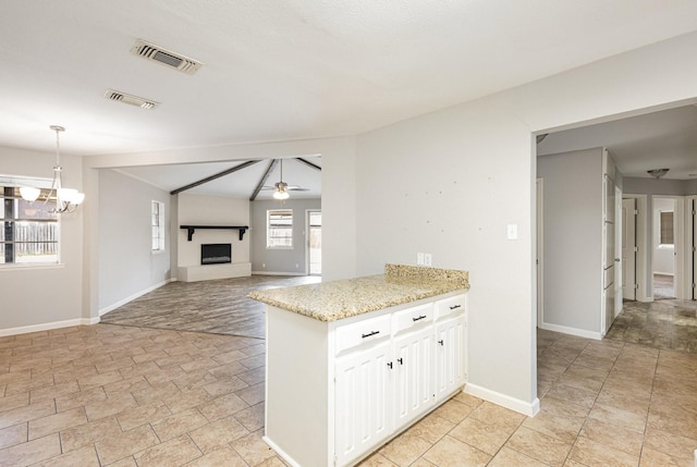 kitchen featuring pendant lighting, visible vents, a fireplace with raised hearth, open floor plan, and white cabinets