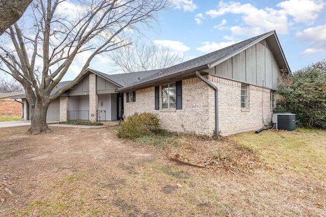 view of front facade with a garage, driveway, a shingled roof, central AC, and brick siding