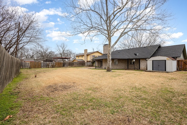 view of yard with a fenced backyard, an outdoor structure, and a storage unit