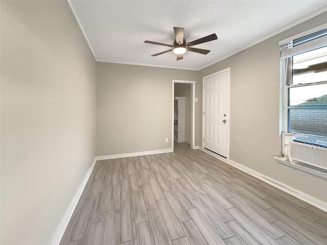 empty room featuring crown molding, ceiling fan, light wood-type flooring, a textured ceiling, and cooling unit