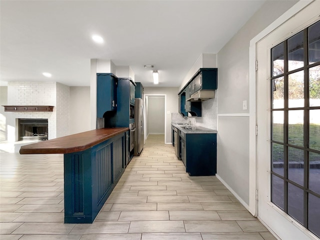 kitchen featuring blue cabinets, stainless steel fridge, a fireplace, and a breakfast bar