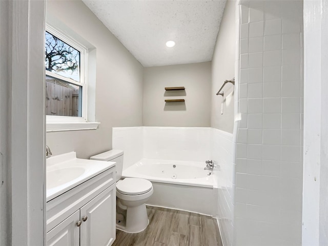 bathroom featuring a textured ceiling, hardwood / wood-style floors, vanity, toilet, and a bathing tub