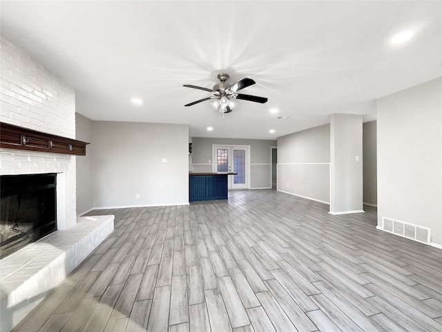 unfurnished living room featuring ceiling fan, light hardwood / wood-style floors, and a fireplace