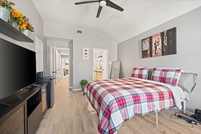 bedroom featuring light wood-type flooring, ceiling fan, vaulted ceiling, and ensuite bath