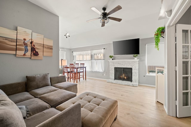 living room featuring a fireplace, ceiling fan, and light wood-type flooring