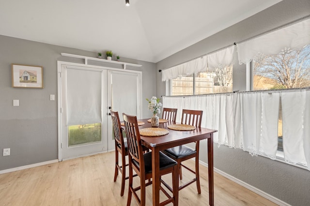 dining space featuring light wood-type flooring and lofted ceiling