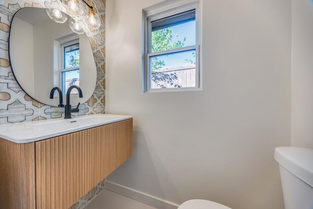 bathroom featuring a wealth of natural light, toilet, and vanity