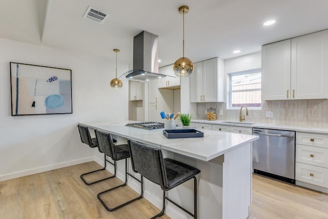 kitchen featuring hanging light fixtures, white cabinets, decorative backsplash, island range hood, and stainless steel appliances