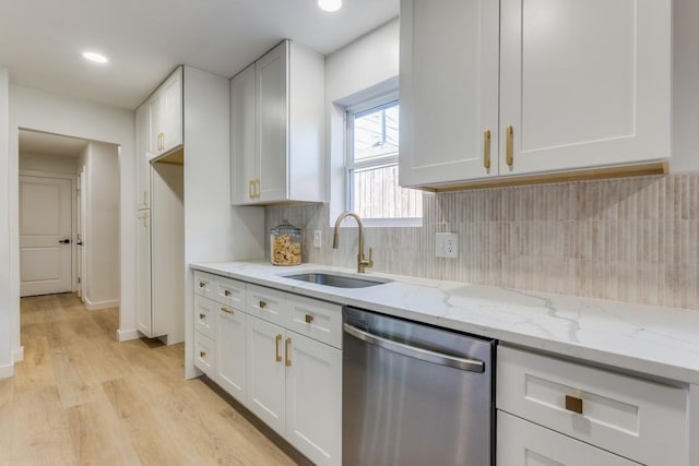 kitchen featuring stainless steel dishwasher, sink, light wood-type flooring, white cabinets, and light stone countertops