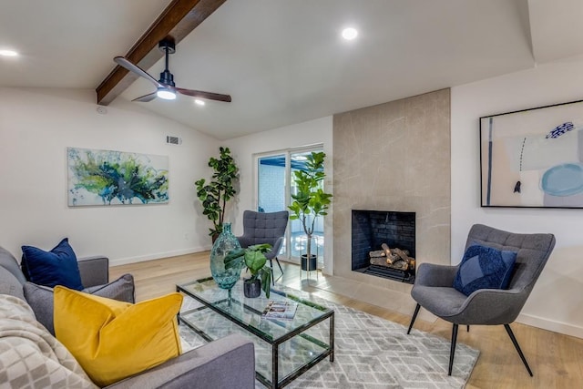 living room with ceiling fan, wood-type flooring, lofted ceiling with beams, and a large fireplace