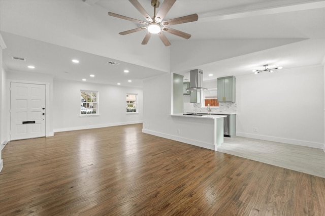 unfurnished living room with ceiling fan, sink, dark wood-type flooring, ornamental molding, and lofted ceiling