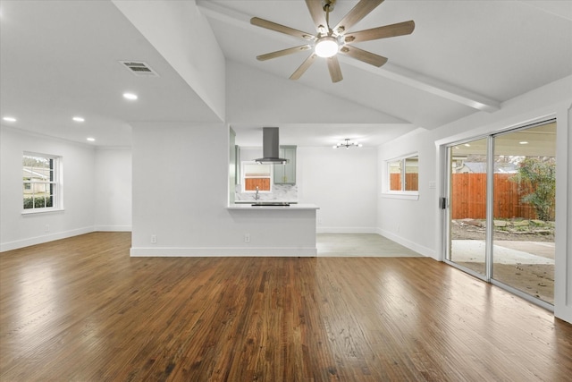 unfurnished living room with hardwood / wood-style flooring, ceiling fan with notable chandelier, and vaulted ceiling with beams