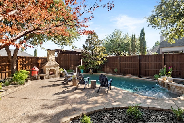 view of pool with pool water feature, a patio, and an outdoor stone fireplace