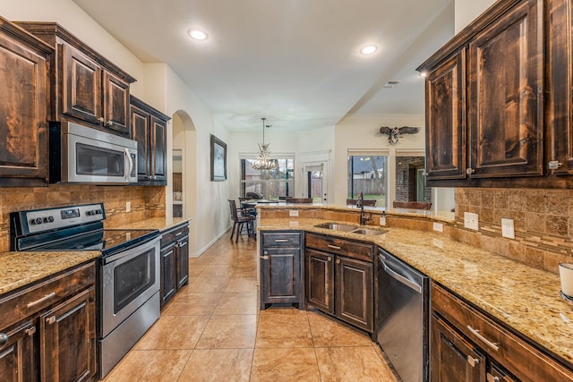 kitchen with backsplash, sink, hanging light fixtures, and appliances with stainless steel finishes