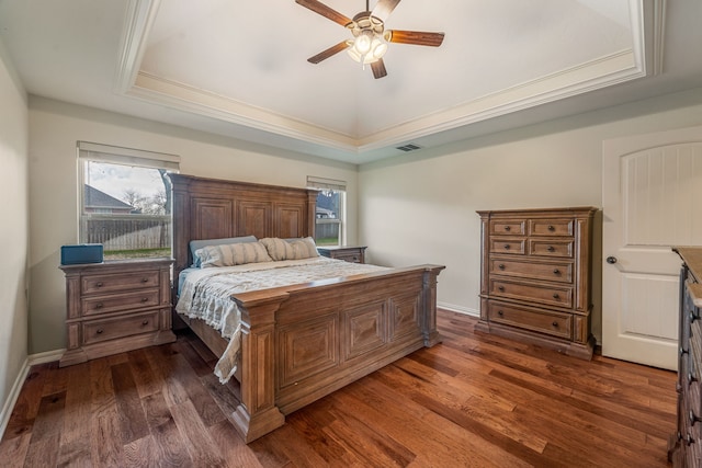 bedroom featuring dark wood-type flooring, multiple windows, ceiling fan, and a raised ceiling