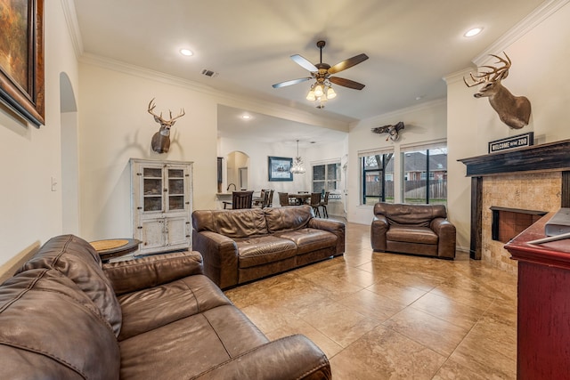 living room featuring ceiling fan, a tile fireplace, crown molding, and light tile patterned flooring