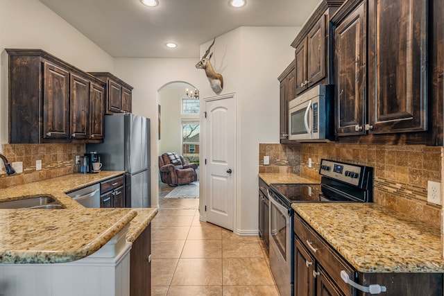 kitchen featuring light stone countertops, appliances with stainless steel finishes, decorative backsplash, sink, and light tile patterned flooring