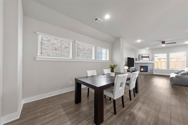 dining room featuring ceiling fan, a tile fireplace, and wood-type flooring