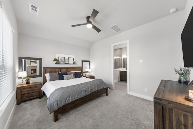 bedroom featuring vaulted ceiling, ensuite bathroom, light colored carpet, and ceiling fan