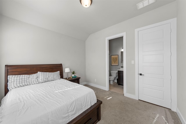 carpeted bedroom featuring vaulted ceiling and connected bathroom